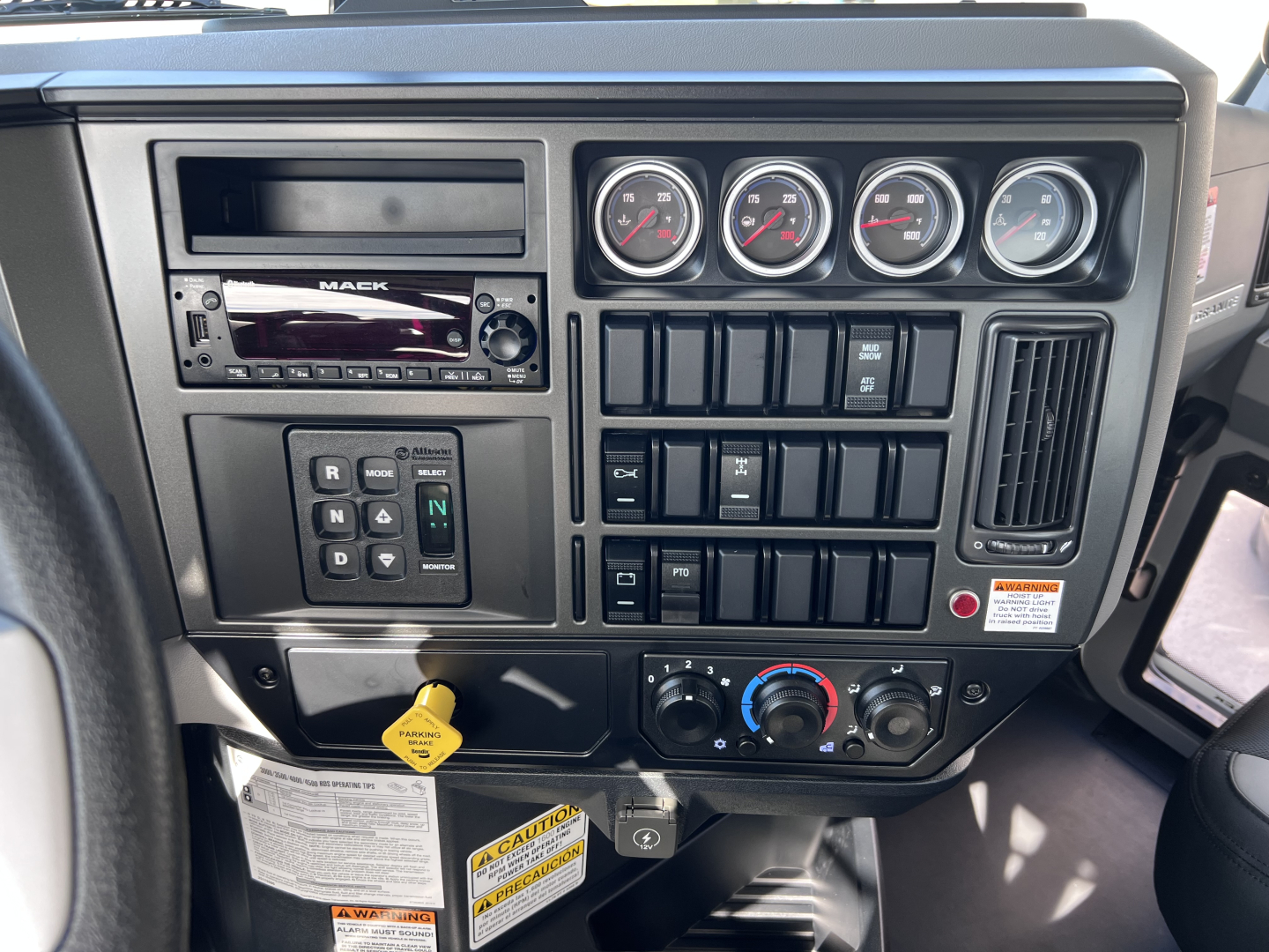 Mack GR64B truck dashboard showing instrument cluster, radio head unit, climate controls, switch panels, and ignition area.