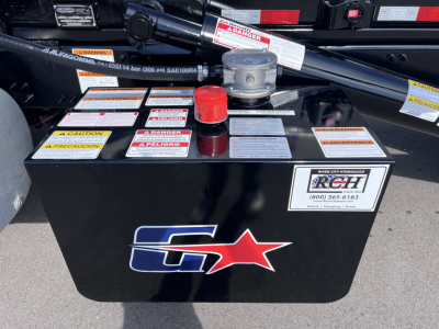 Rolloff truck battery area with warning labels and red loss cap on top of battery box showing G star logo.