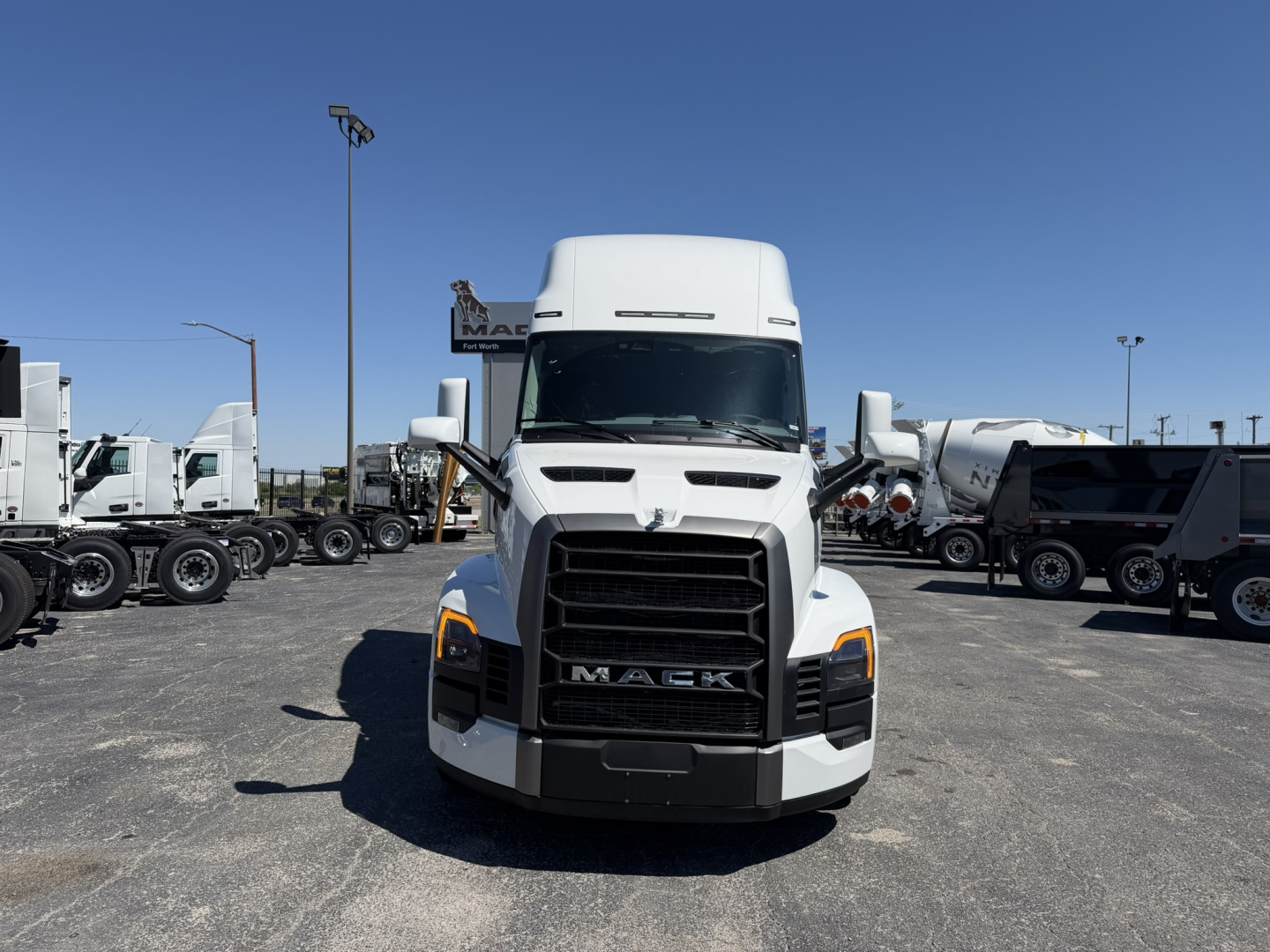 Front view of a white Mack PR64T76H semi-truck in a dealership lot, with bold grille, headlights, and 