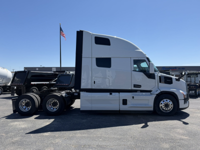 Side view of a white Mack PR64T76H truck tractor in a dealership lot, with sleeper cab and dual rear axles, VIN and stock number not visible on the side.