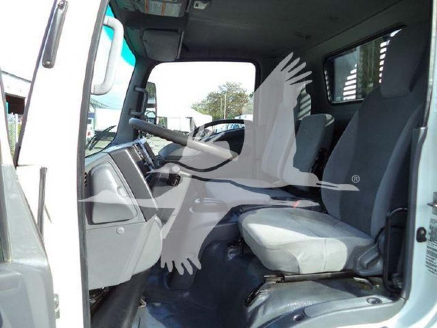 Isuzu NRR cab interior view showing driver and passenger seats with steering wheel and dashboard.