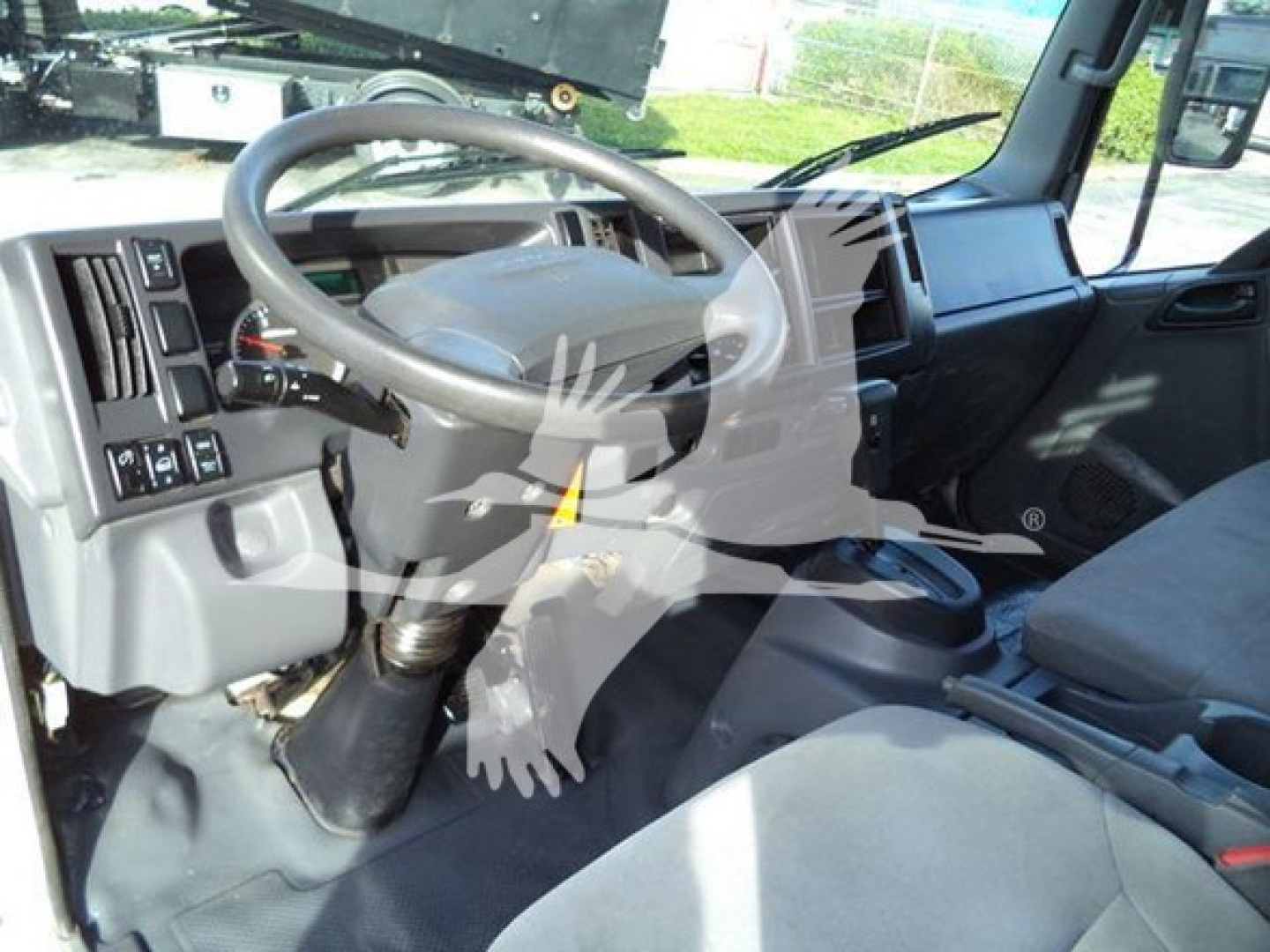 Isuzu NRR truck cabin interior showing steering wheel and dashboard with controls.