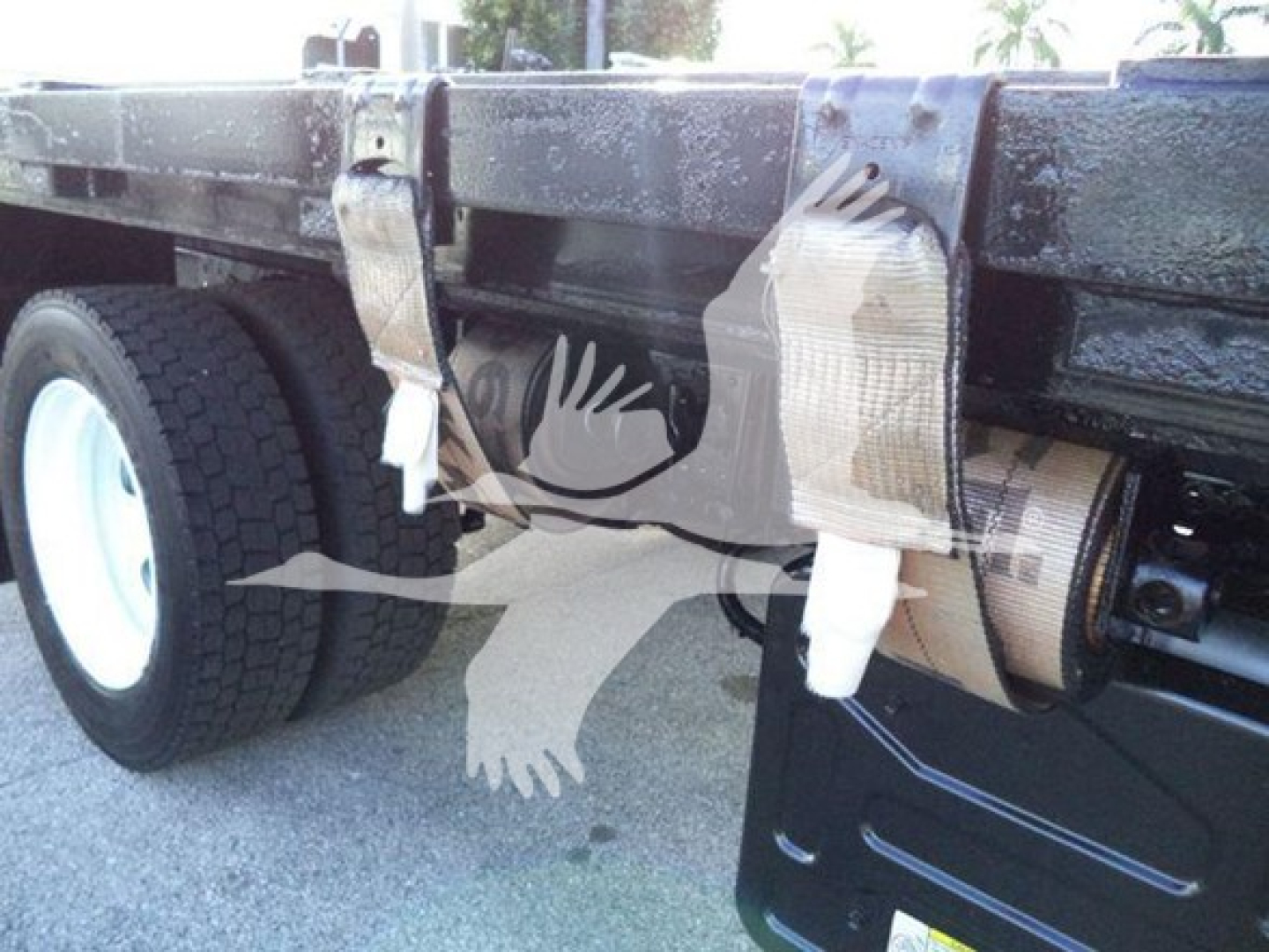 Isuzu NRR flatbed truck rear showing bumper area with duct tape and protective padding on the frame and spare wheel visible.