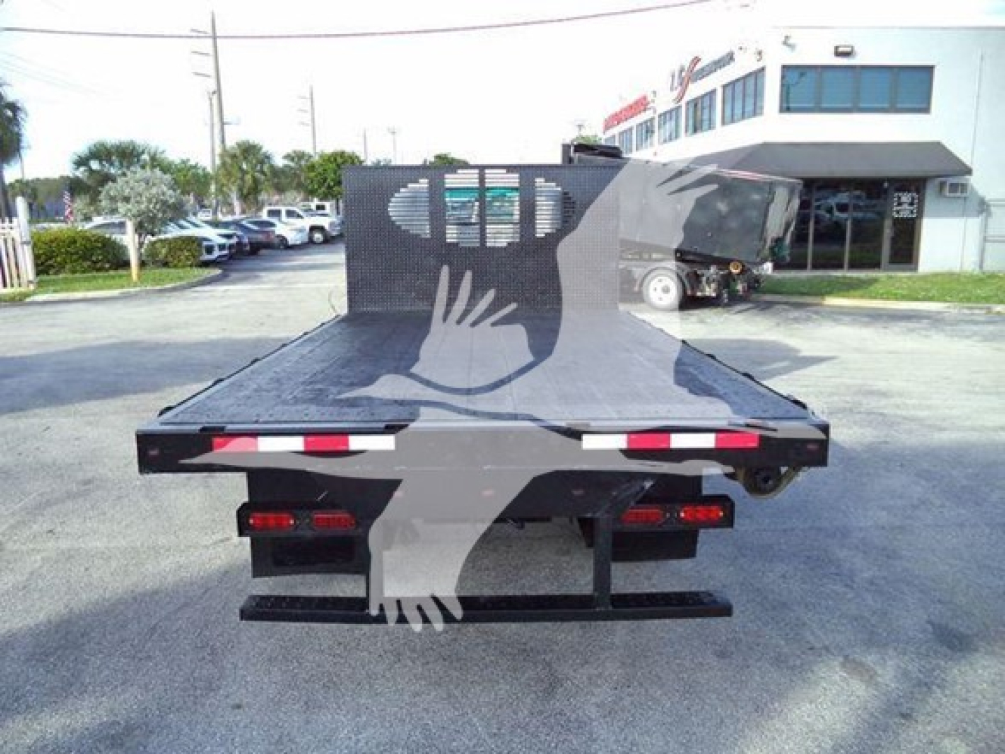 Isuzu flatbed truck rear view showing flatbed with taillights and bumper. VIN/stock/category not visible on image, generic scene in lot.