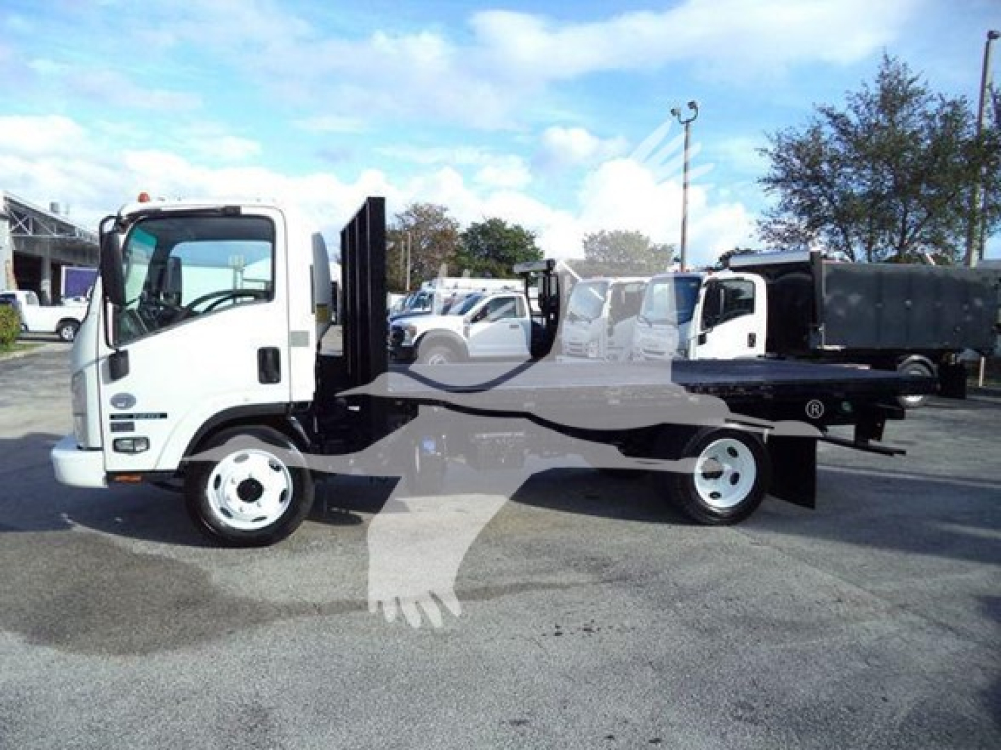 Isuzu NRR flatbed truck side view showing cab, flatbed chassis, and dually rear wheels.
