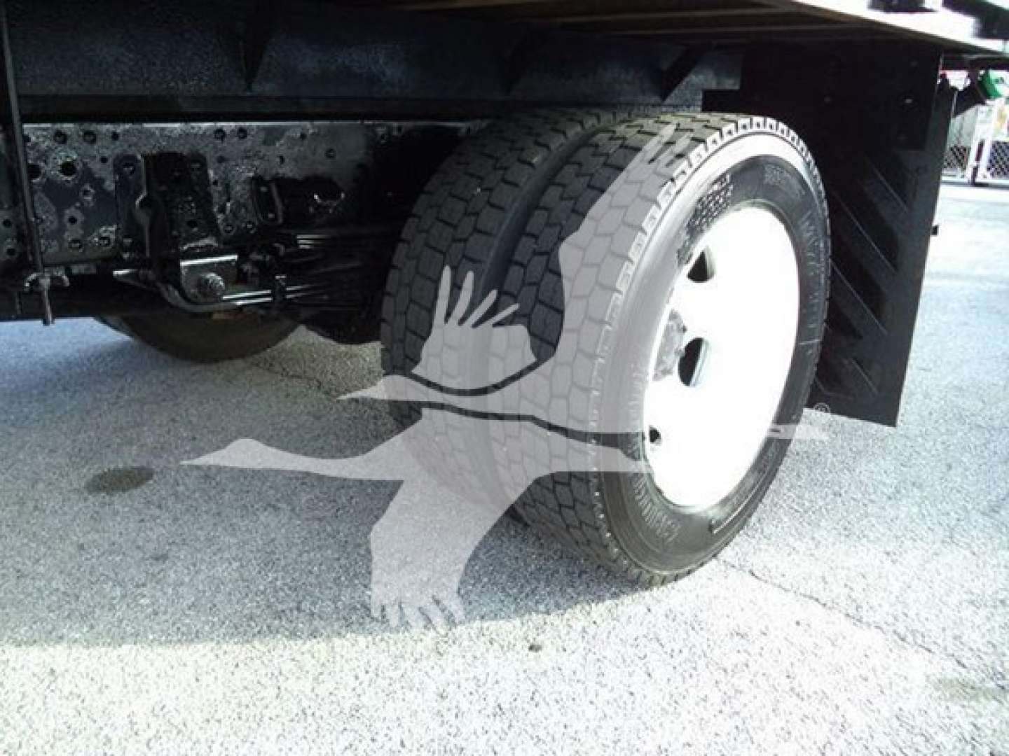 Isuzu NRR truck undercarriage showing front wheel and suspension with flatbed in view.