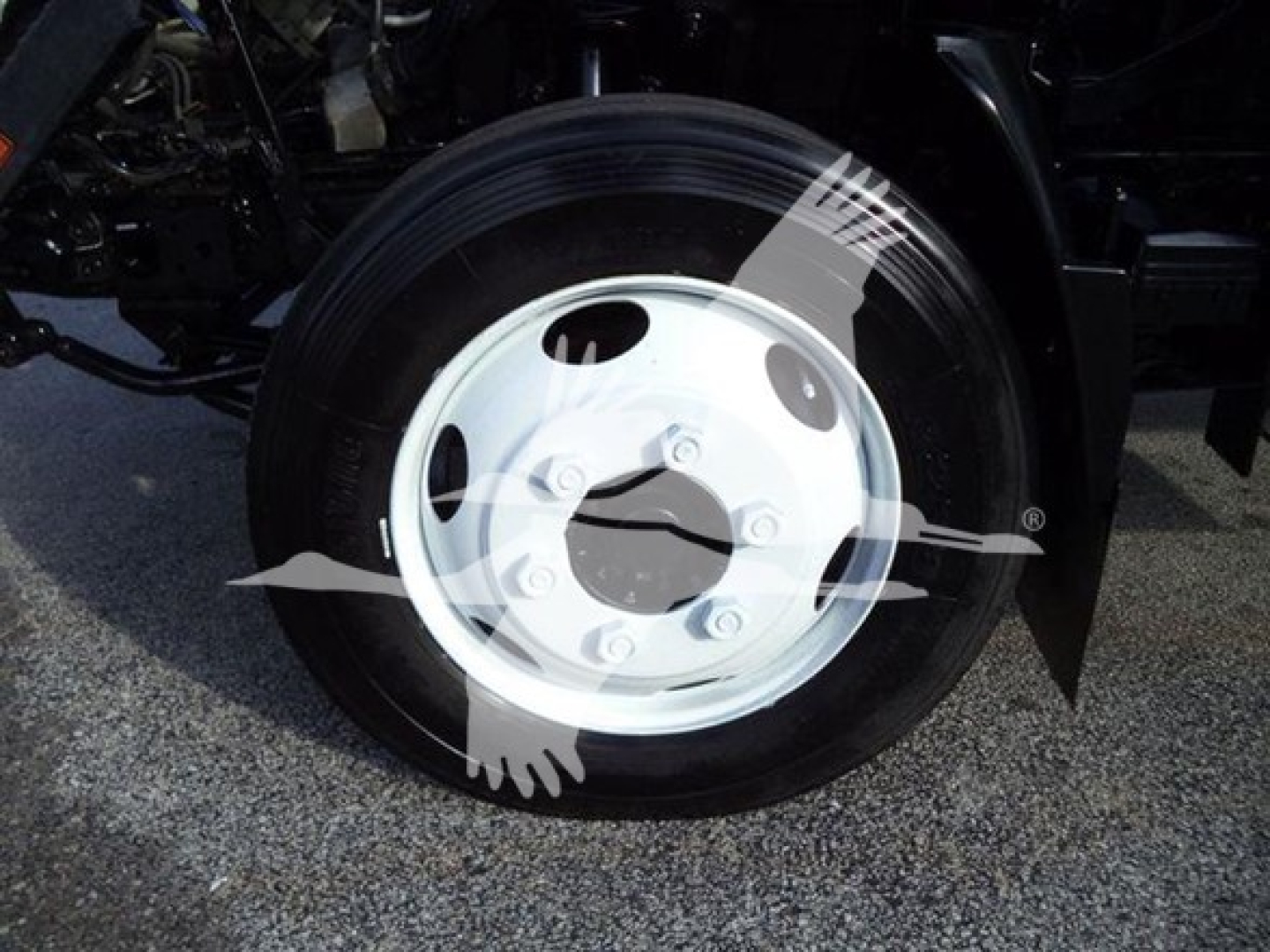 Wheel and tire close-up on Isuzu NRR truck showing white steel wheel with lug nuts and black tire.