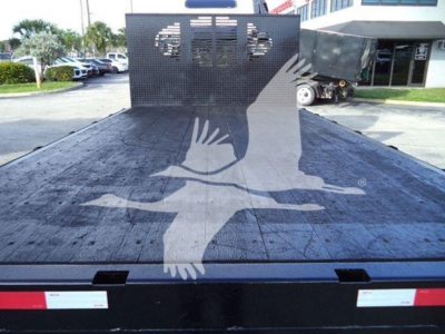 Flatbed truck bed of a 2020 Isuzu NRR with a big bird graphic on the wooden surface and a perforated metal headboard at the front; no visible text on the bed.