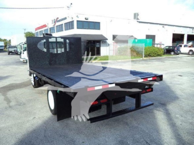 Isuzu NRR flatbed truck in a dealership lot showing a flatbed with a metal cargo area and rear bumper.