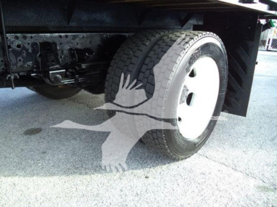 Isuzu NRR truck undercarriage showing front wheel and suspension with flatbed in view.
