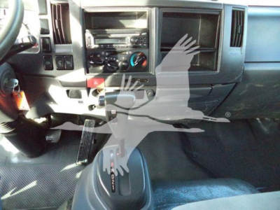 Isuzu NRR truck interior showing center console with climate controls, radio, and gear selector. Partial dashboard and pedals visible.