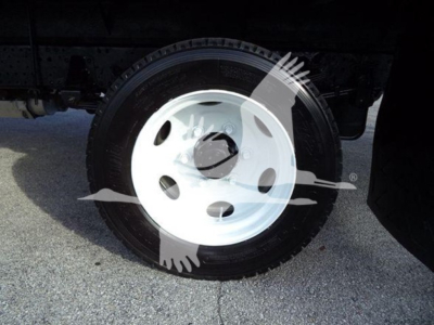 Isuzu NRR wheel and tire close-up showing white steel rim and tire sidewall.
