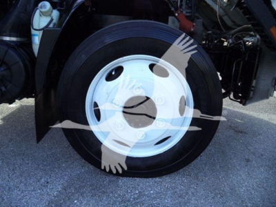 Isuzu NRR wheel and front tire visible with white steel wheel and hub in a flatbed truck undercarriage.