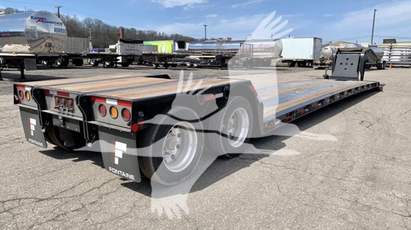  Fontaine Renegade N12 lowboy trailer showing dual rear lights, wooden deck, steel edges, and tandem axles with black mud flaps.