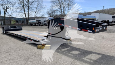 Fontaine Renegade N12 lowboy trailer in a storage lot, showing a long flatbed deck and gooseneck with wheel wells and reflective safety stripe.