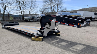 Lowboy trailer showing Fontaine Renegade N12 branding with long flat deck and gooseneck, black frame, and reflective safety stripes.