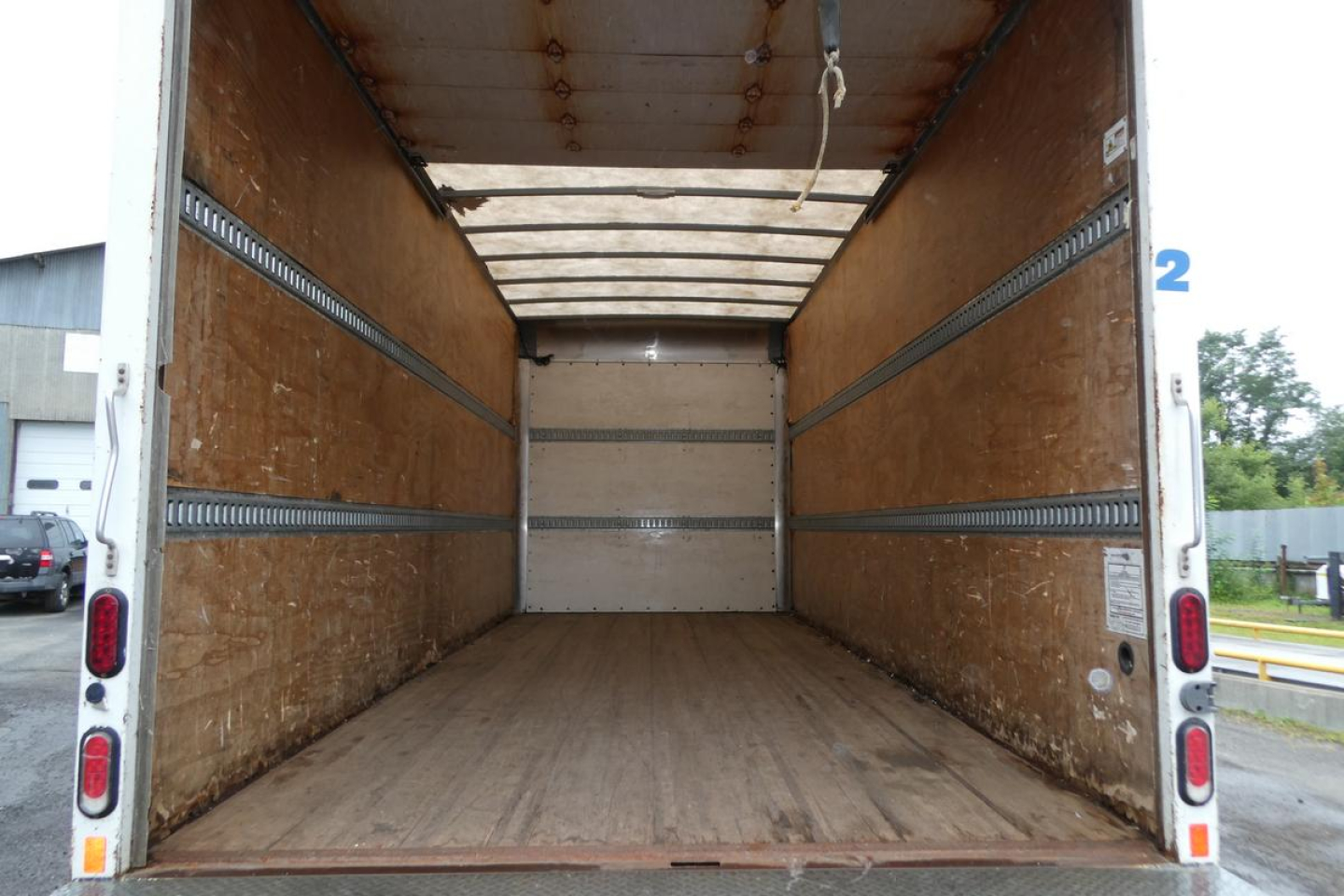 Truck cargo area of a 2019 Mitsubishi Fuso Canter FE140 box truck showing empty wooden walls and floor.