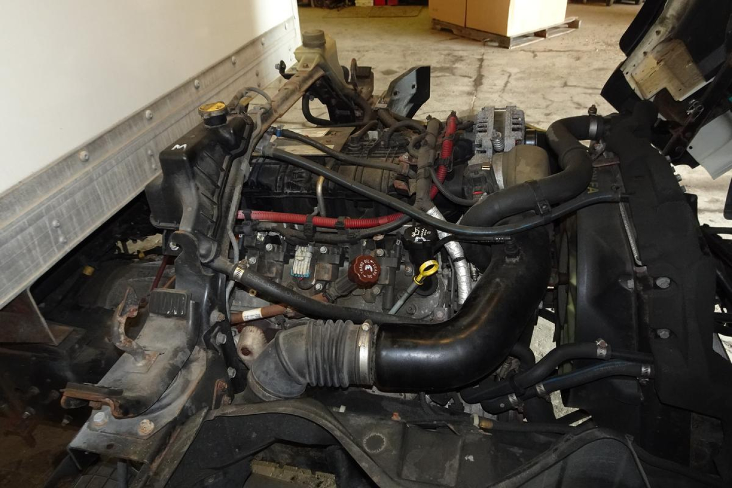 Engine bay of a 2019 Mitsubishi Fuso Canter FE140 showing engine components, hoses, and intake manifold.