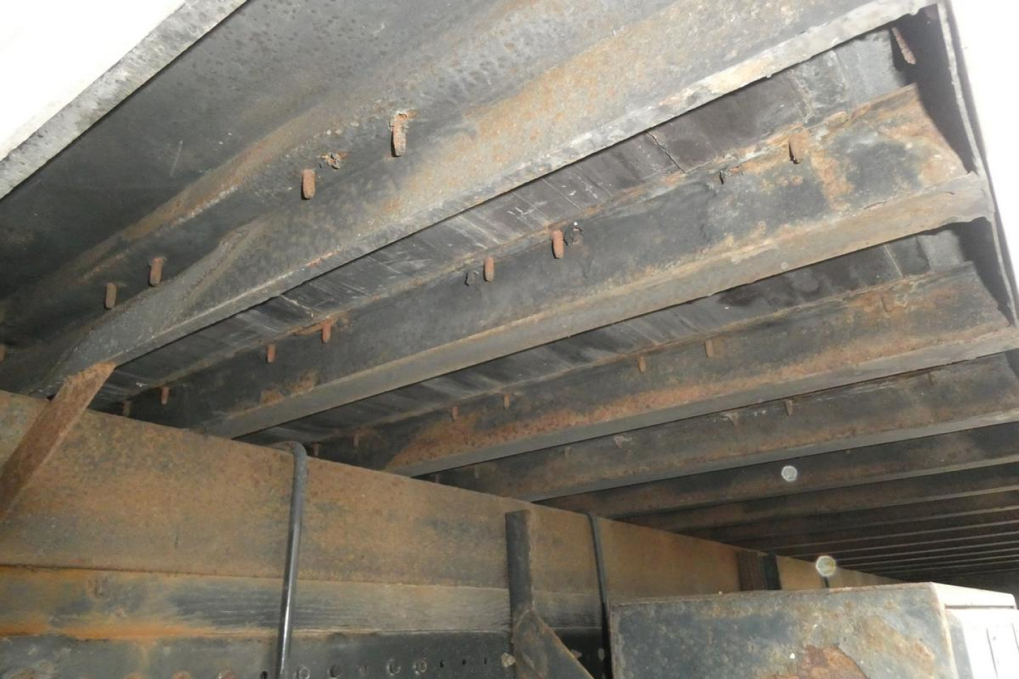 Underbody view of a box truck showing crossmembers and frame rails with surface rust.