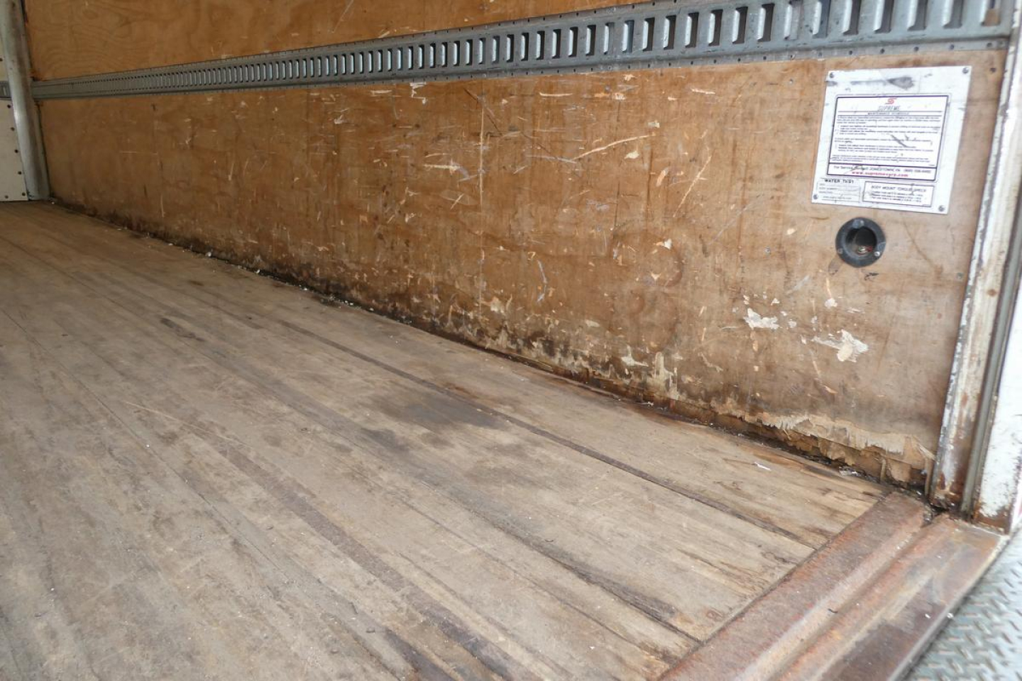 Mitsubishi Fuso Canter FE140 box truck interior cargo area with wooden walls and floor showing side panels and a small inspection label