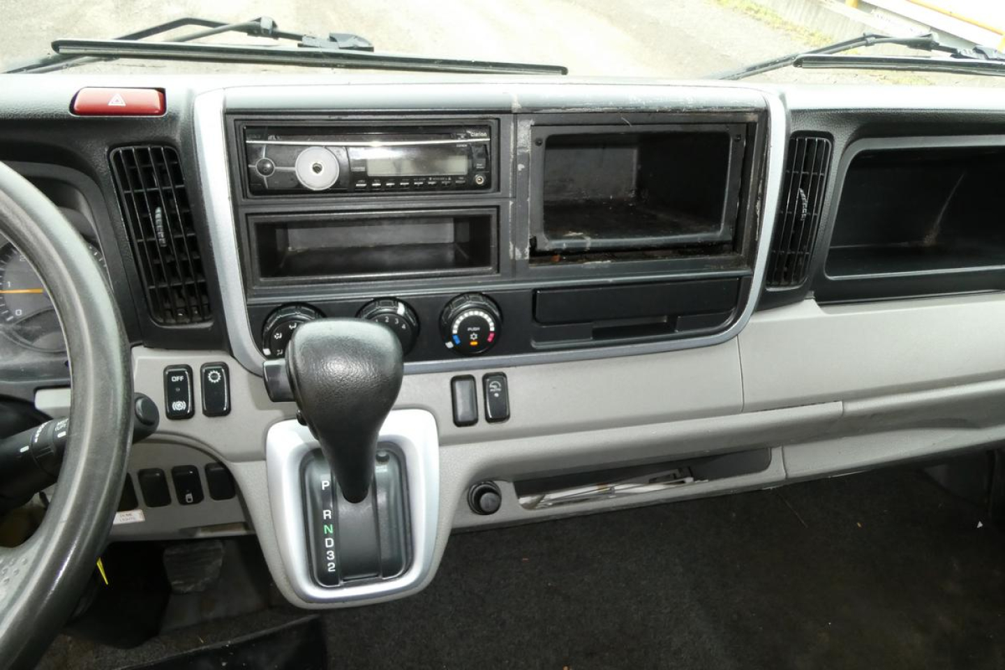 Dashboard area and gear selector of Mitsubishi Fuso Canter FE140 interior with radio and empty console bay.