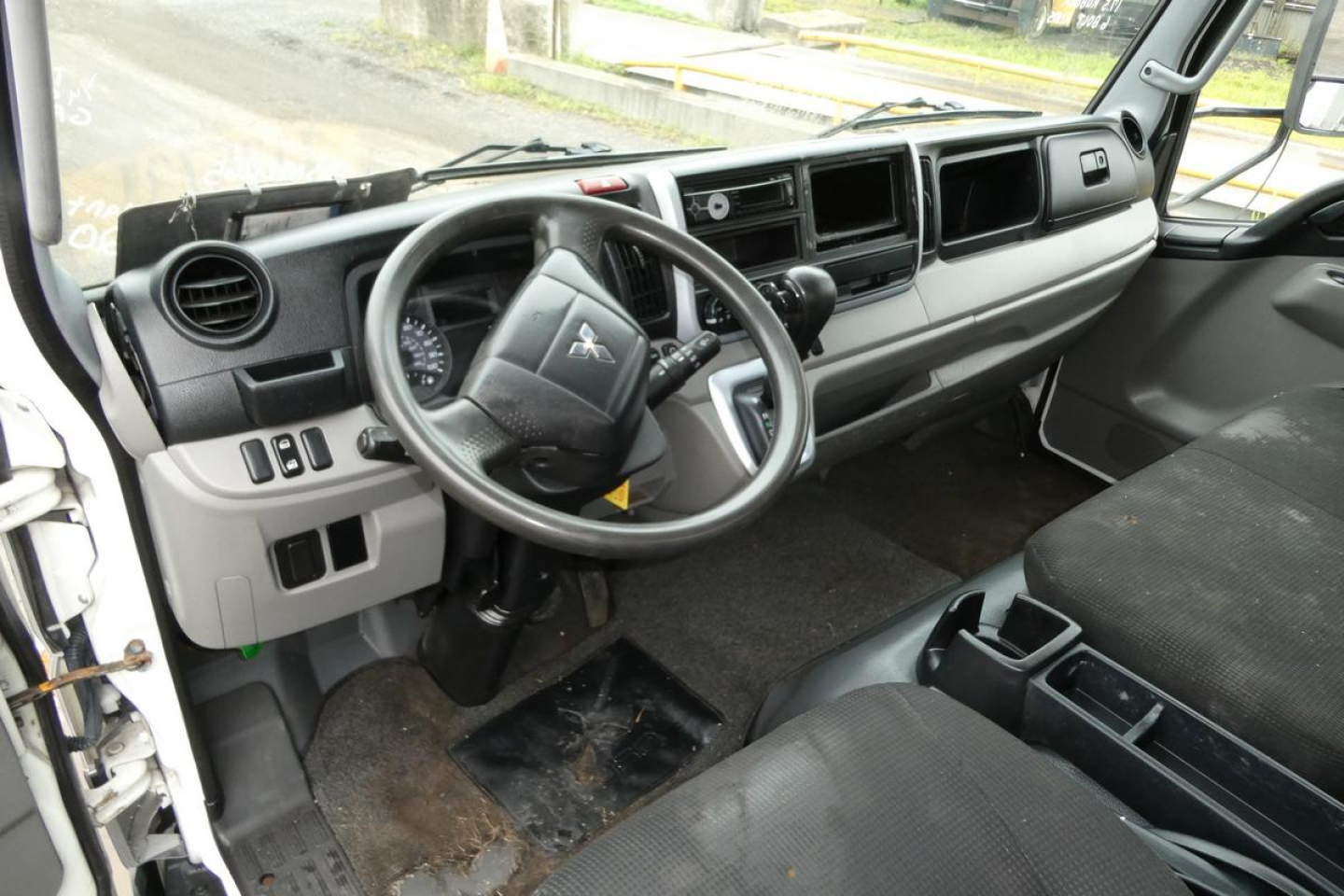 Cab interior of Mitsubishi Fuso Canter FE140 showing steering wheel and dashboard