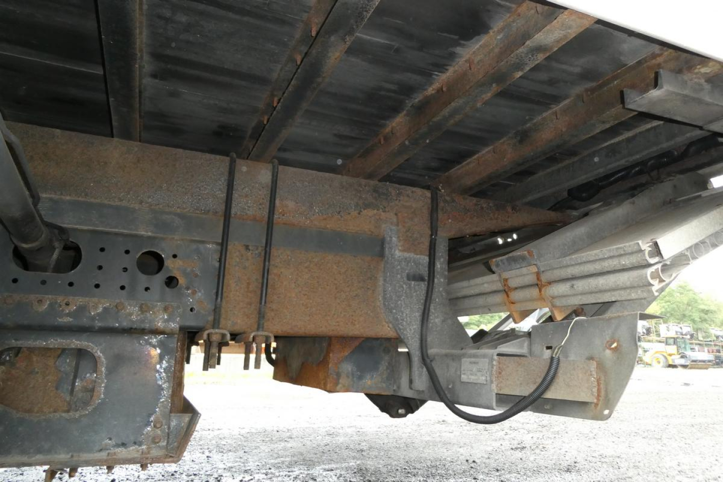 Underbody view of a Mitsubishi Fuso Canter FE140 truck showing rusted frame components and underside structure.