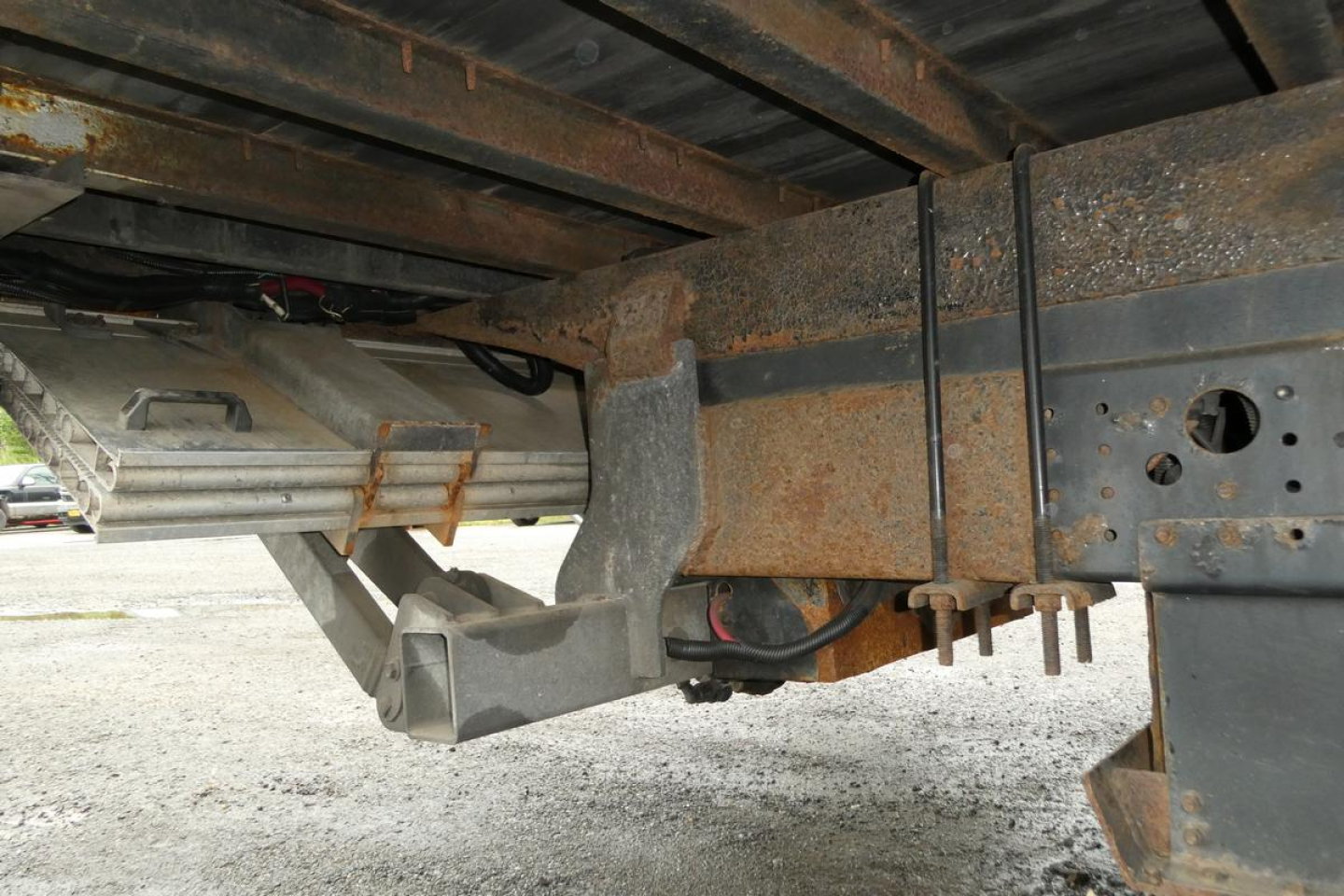 Mitsubishi Fuso Canter FE140 undercarriage showing chassis frame and hitch area with rust and spare wheel cradle, side view of bumper support and cross member.