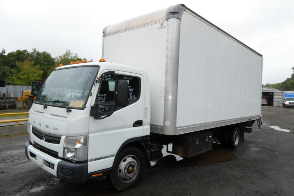 Box truck side view showing Mitsubishi Fuso Canter FE140 with box body and cab in foreground.