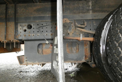 Chassis underside of a 2019 Mitsubishi Fuso Canter FE140 box truck showing frame, suspension, and wheel area with rusted components and mounting brackets.