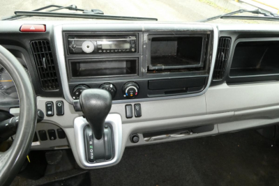 Dashboard area and gear selector of Mitsubishi Fuso Canter FE140 interior with radio and empty console bay.