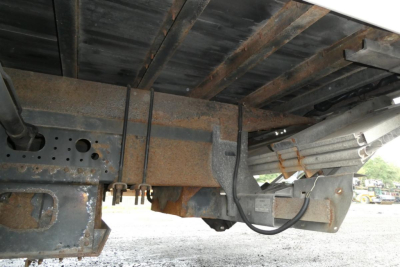 Underbody view of a Mitsubishi Fuso Canter FE140 truck showing rusted frame components and underside structure.