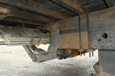 Mitsubishi Fuso Canter FE140 undercarriage showing chassis frame and hitch area with rust and spare wheel cradle, side view of bumper support and cross member.