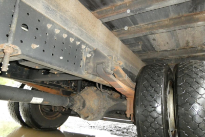 Front underside view of a Mitsubishi Fuso Canter FE140 showing dual rear wheels, axle, frame, and suspension components.