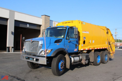 Truck view of a blue International WorkStar 7400 packer body in yellow, side angle showing front grille and dual rear axles.