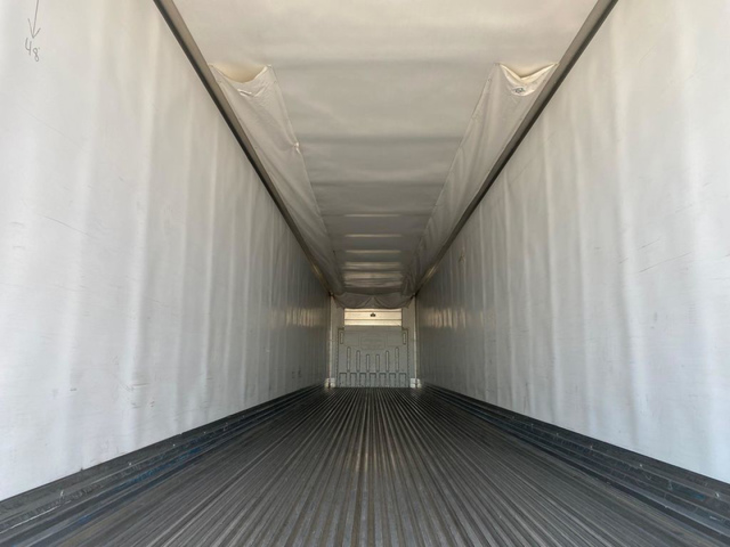 Trailer cargo interior view of a 2021 Utility reefer showing long white insulated walls and ribbed floor, empty trailer with rear door. Contains VIN 1UYVS2535M2382620 and stock U91003 information text not visible in image.