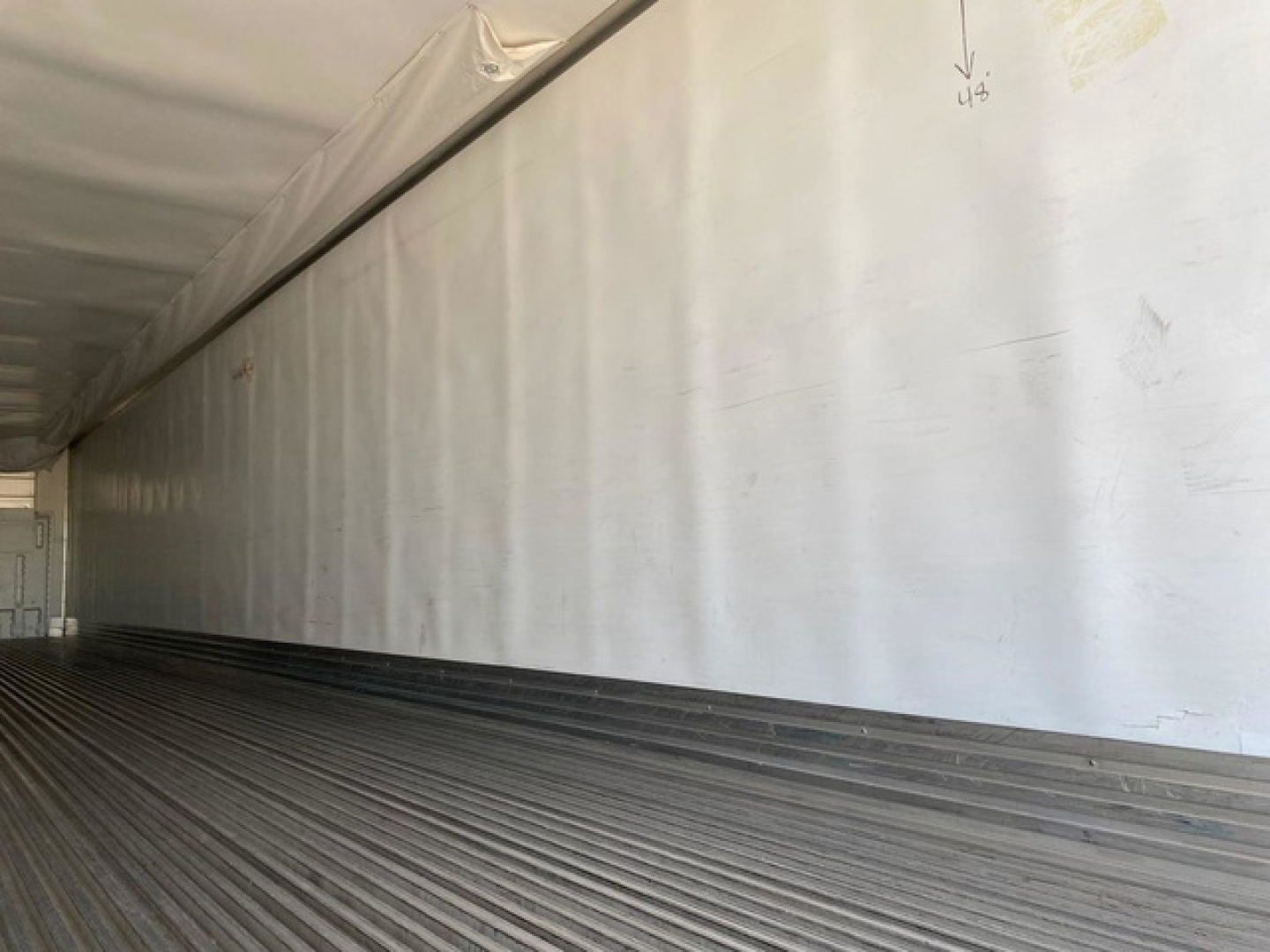 Trailer interior with white refrigerated box, long corrugated metal floor, and smooth side walls.