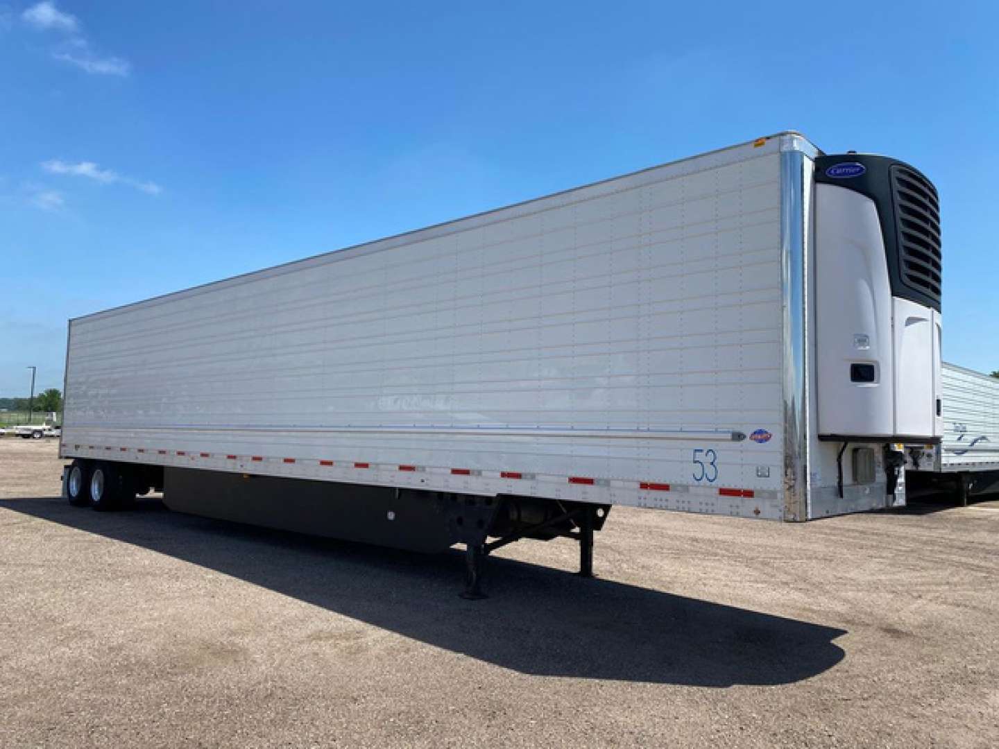 Trailer side view of a 2021 Utility Reefer refrigerated trailer showing third axle, curbside view, insulated aluminum body, and white Thermo King unit at front. Text visible includes stock number 53 and small decals.