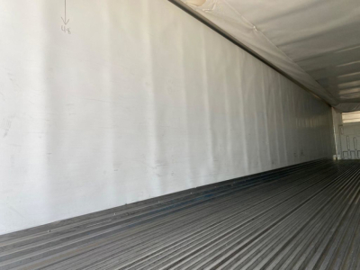 Trailer interior wall and floor of a refrigerated utility trailer showing metal ribbed floor and white wall with markings