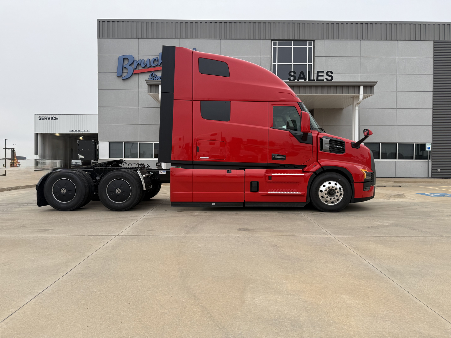 Mack PR64T76H conventional sleeper tractor in red, side view, showing cab and rear axle with fuel tanks and chassis.