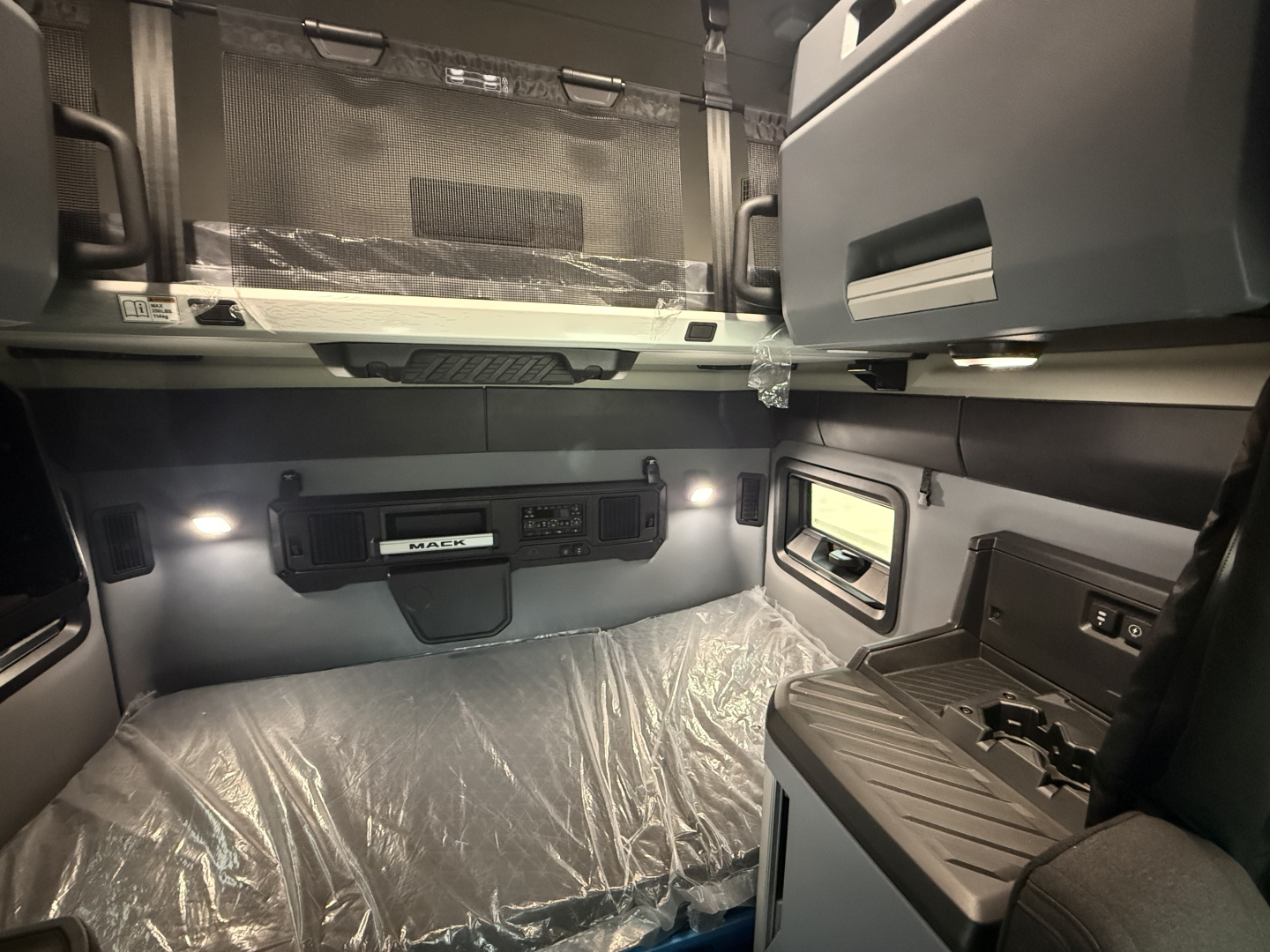 Mack PR64T76H truck interior sleeper cab showing bunk area with storage shelf and control panel