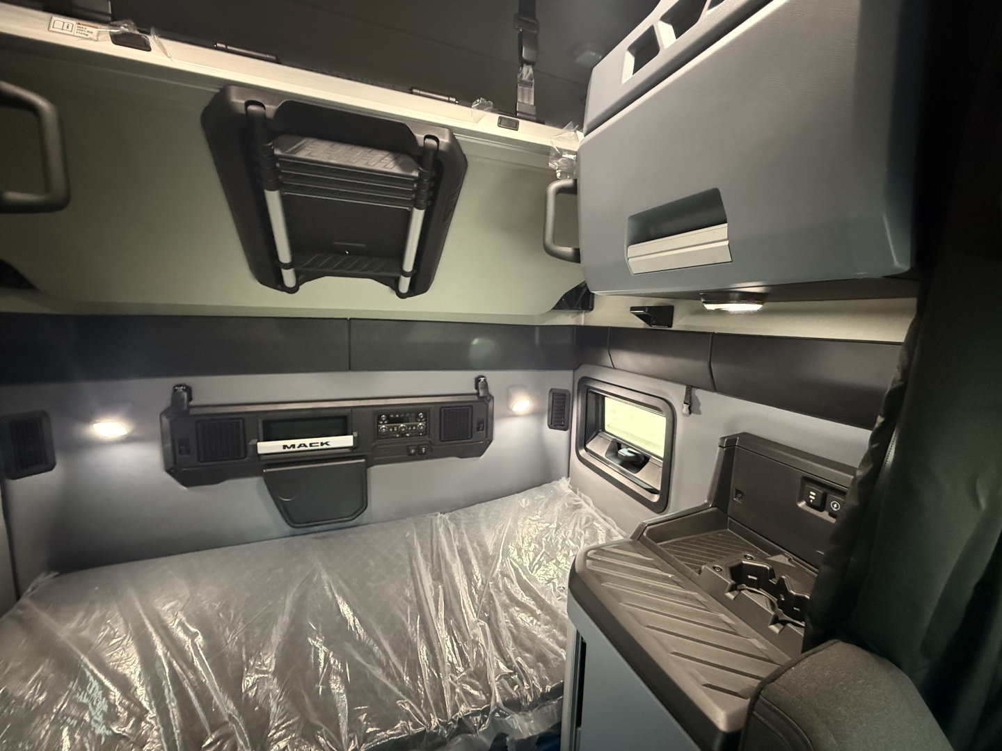Mack PR64T76H sleeper cab interior showing overhead storage, bunk area, and control panel with Mack branding.