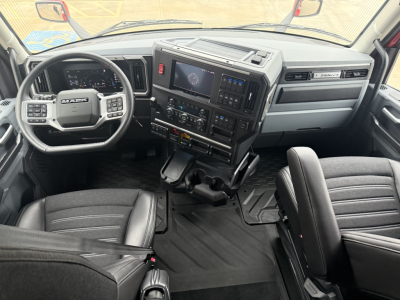 Mack PR64T76H truck cab interior showing steering wheel, dashboard with large touchscreen, center console, and driver/passenger seats.