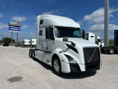 2020 Volvo VNL64T760 tractor truck in white with long sleeper cab, front grille and headlights visible; dealership lot in background.