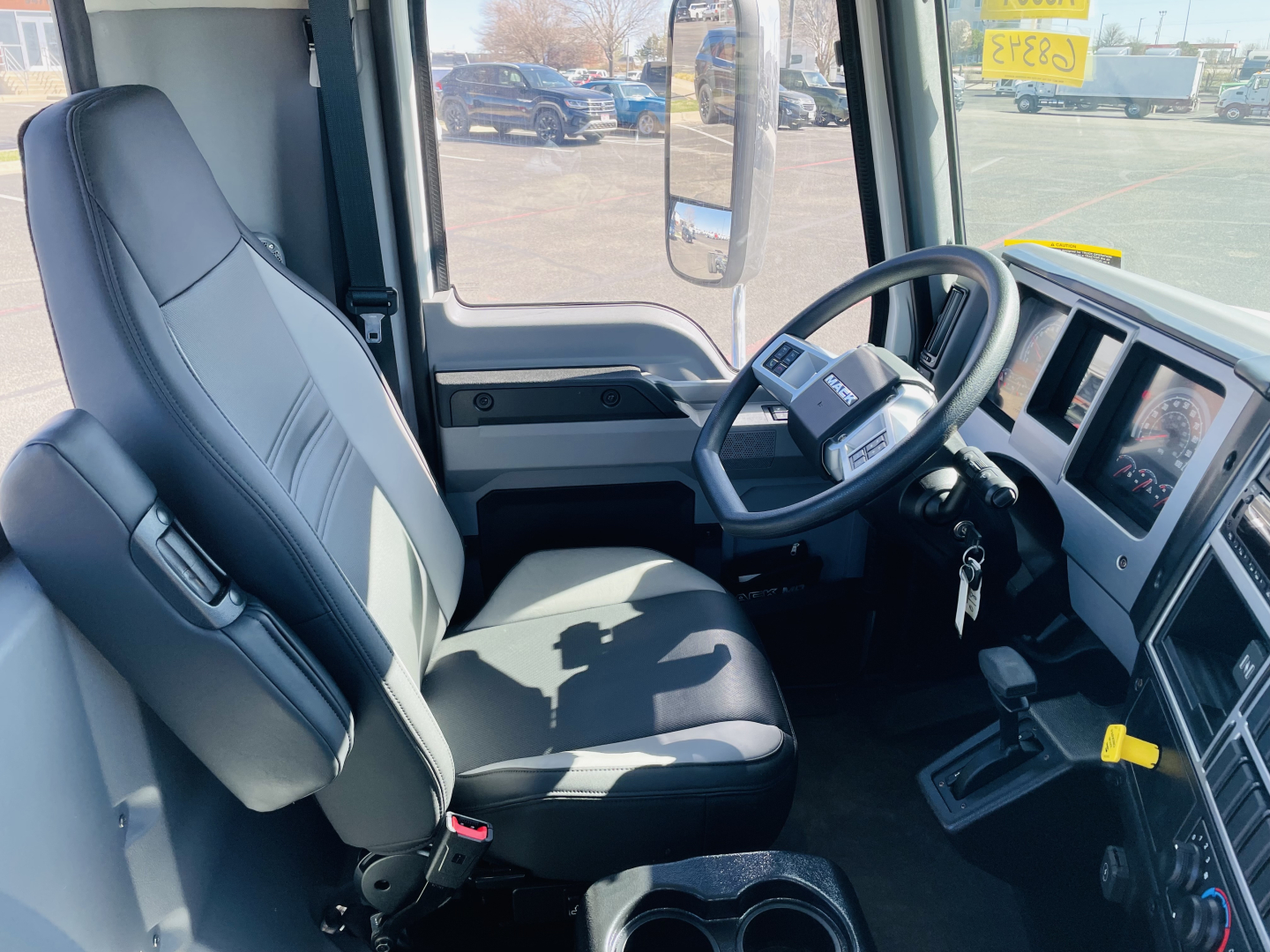 Trailer truck cab interior of a 2026 Mack MD6 showing driver seat, steering wheel, dashboard, and gear selector.