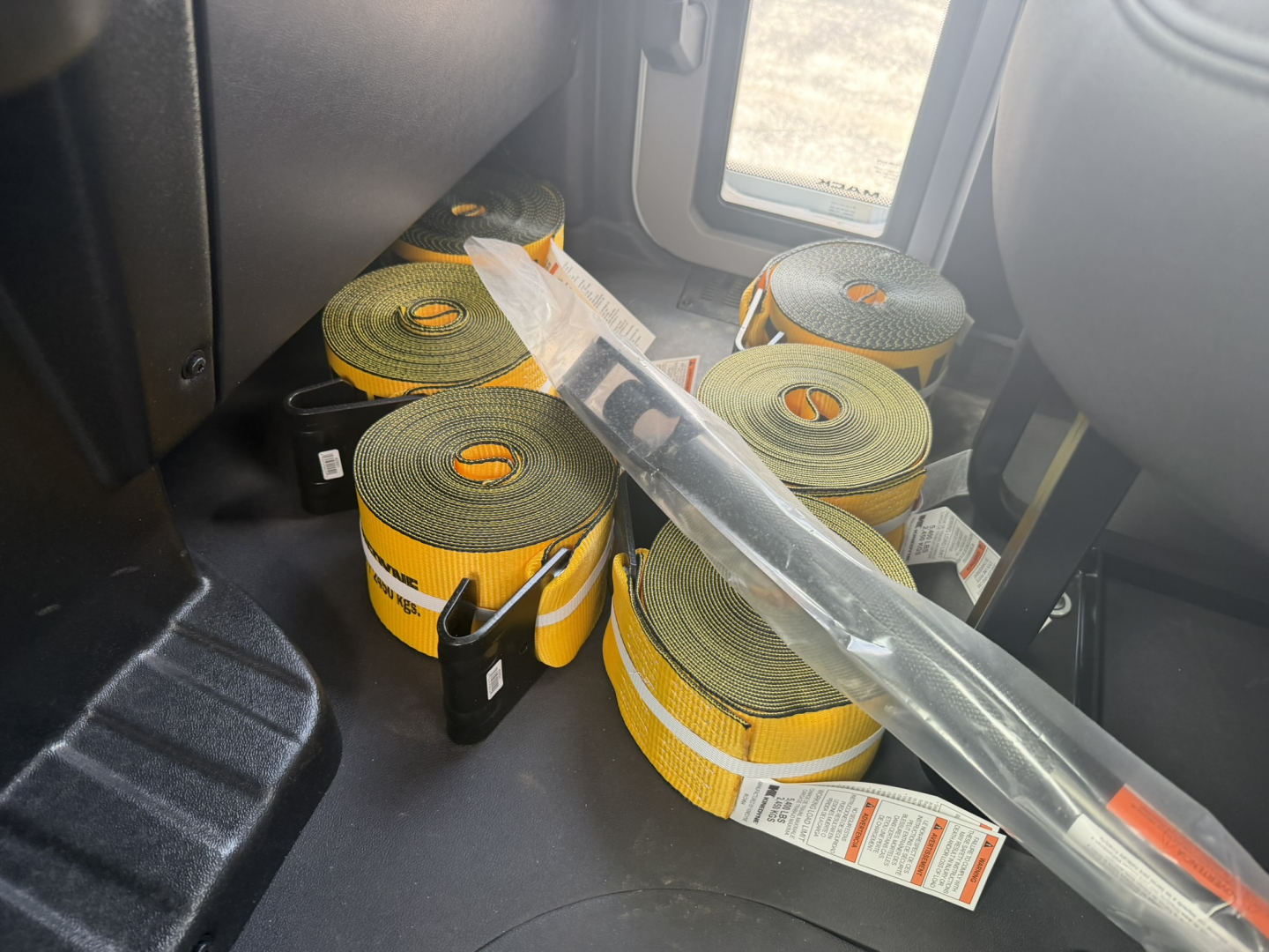 Interior of a new Mack MD6 truck cabin with multiple rolled straps (load restraints) on the floor.
