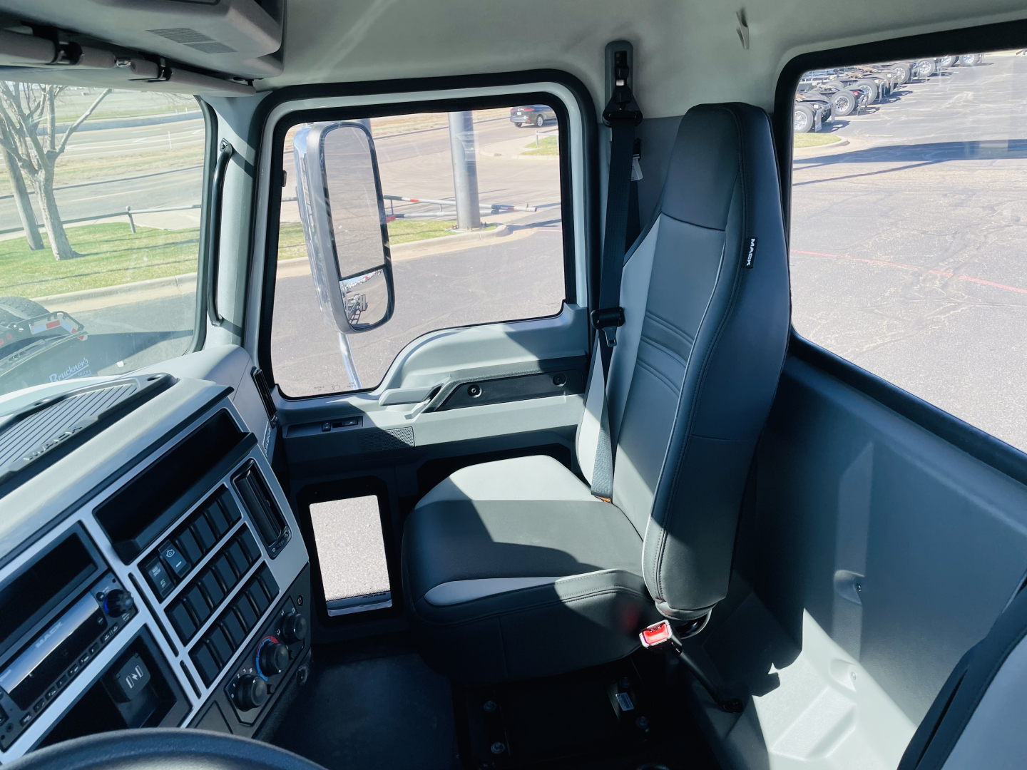 Interior of a new Mack MD6 truck cab showing driver seat, steering wheel area, and dashboard accents.