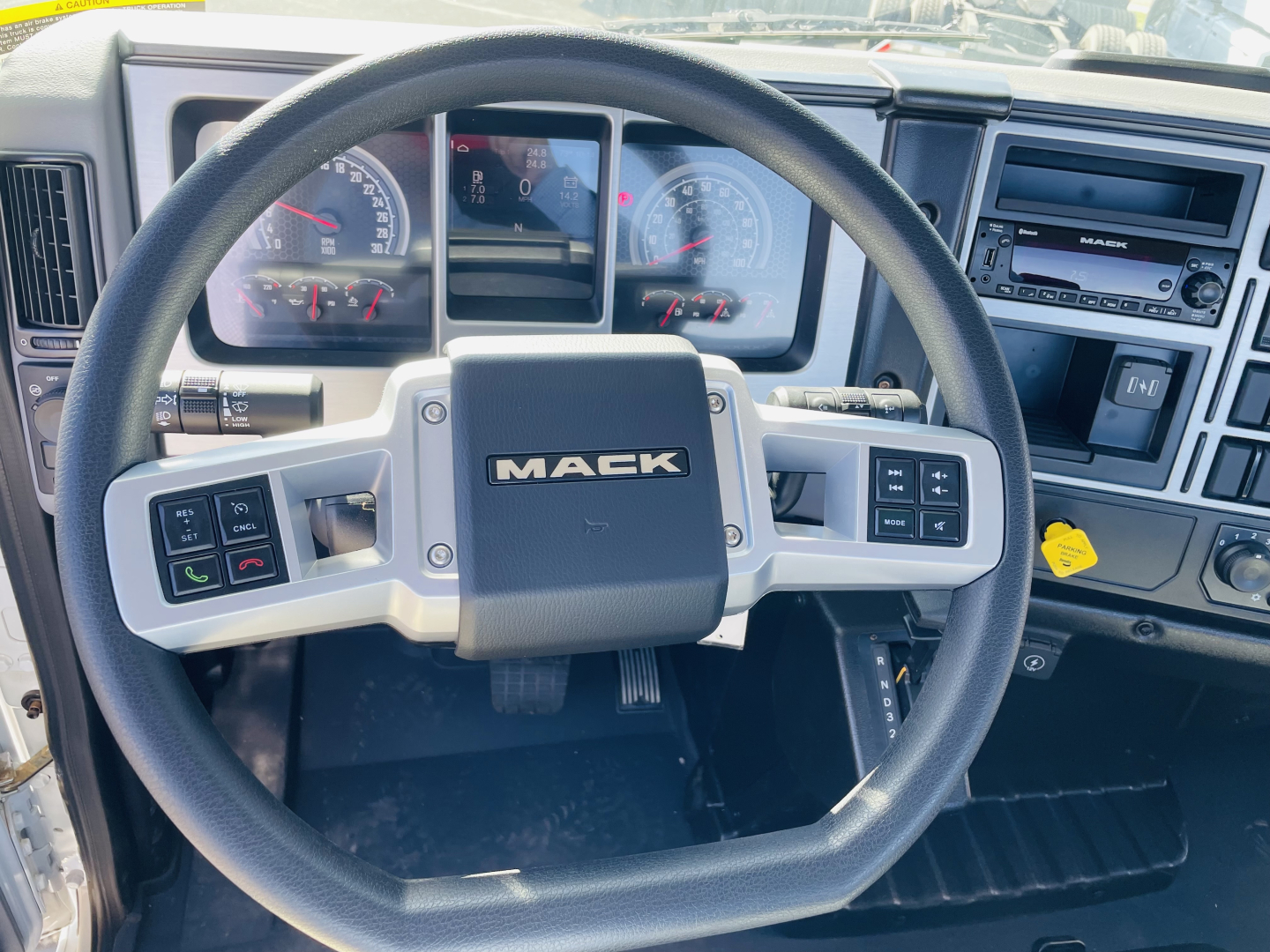 Mack MD6 truck interior steering wheel view showing dashboard gauges and control buttons