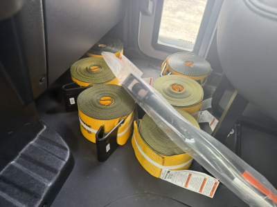 Interior of a new Mack MD6 truck cabin with multiple rolled straps (load restraints) on the floor.