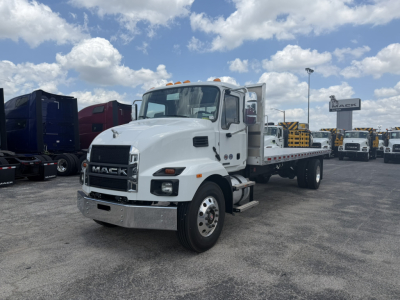 Mack MD6 flatbed truck in a dealership lot, white cab, chrome front bumper, with flatbed and yellow safety beacon lights on cab roof.